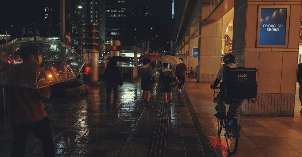 夜間に傘を差して片手運転をする自転車のイラスト。無灯火や傘さし運転の危険性を表現。
