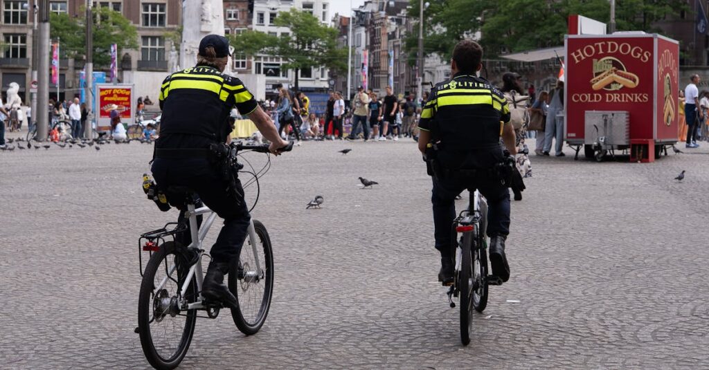 警察官が通勤中の自転車違反を指導している場面。信号無視やスマホ操作の取り締まり実態をイメージした説明画像。