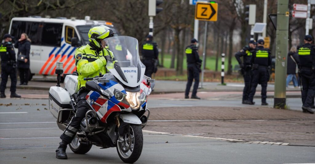 警察官が通勤中の自転車違反を指導している場面。信号無視やスマホ操作の取り締まり実態をイメージした説明画像。