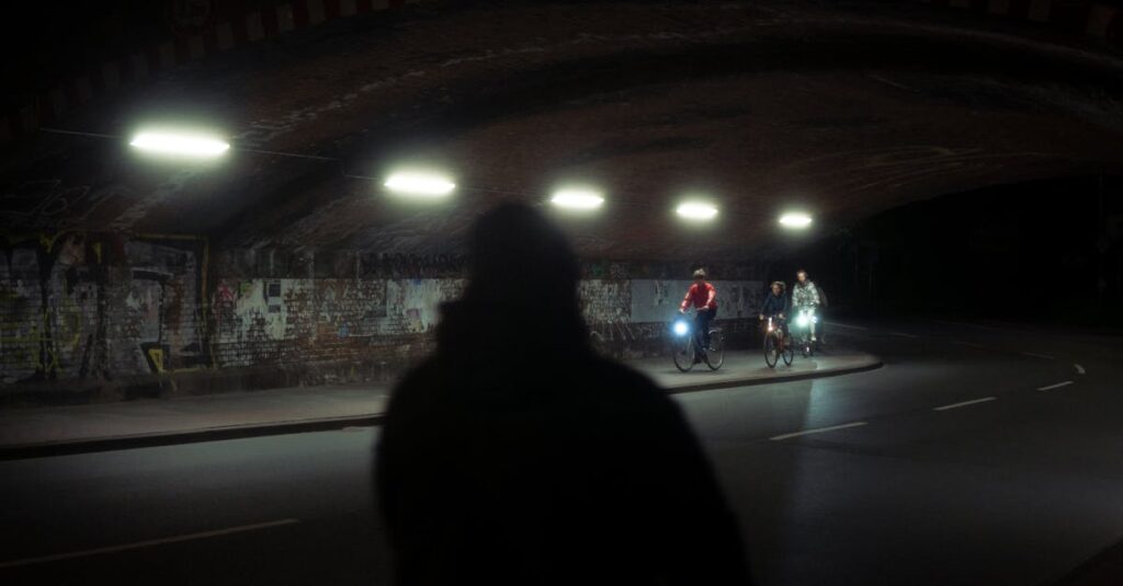 夜間にライトを点灯して走る自転車のイラスト。無灯火走行の危険性と視認性の重要性を説明。