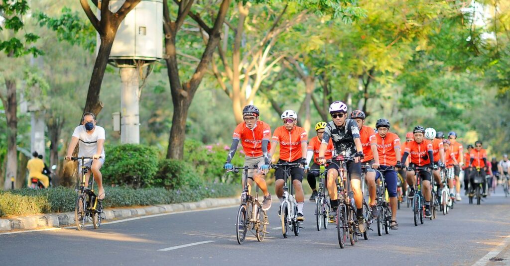 自転車利用者・歩行者・車が調和する交通社会のイラスト。安全意識の向上を象徴する明るい街並みを描く。